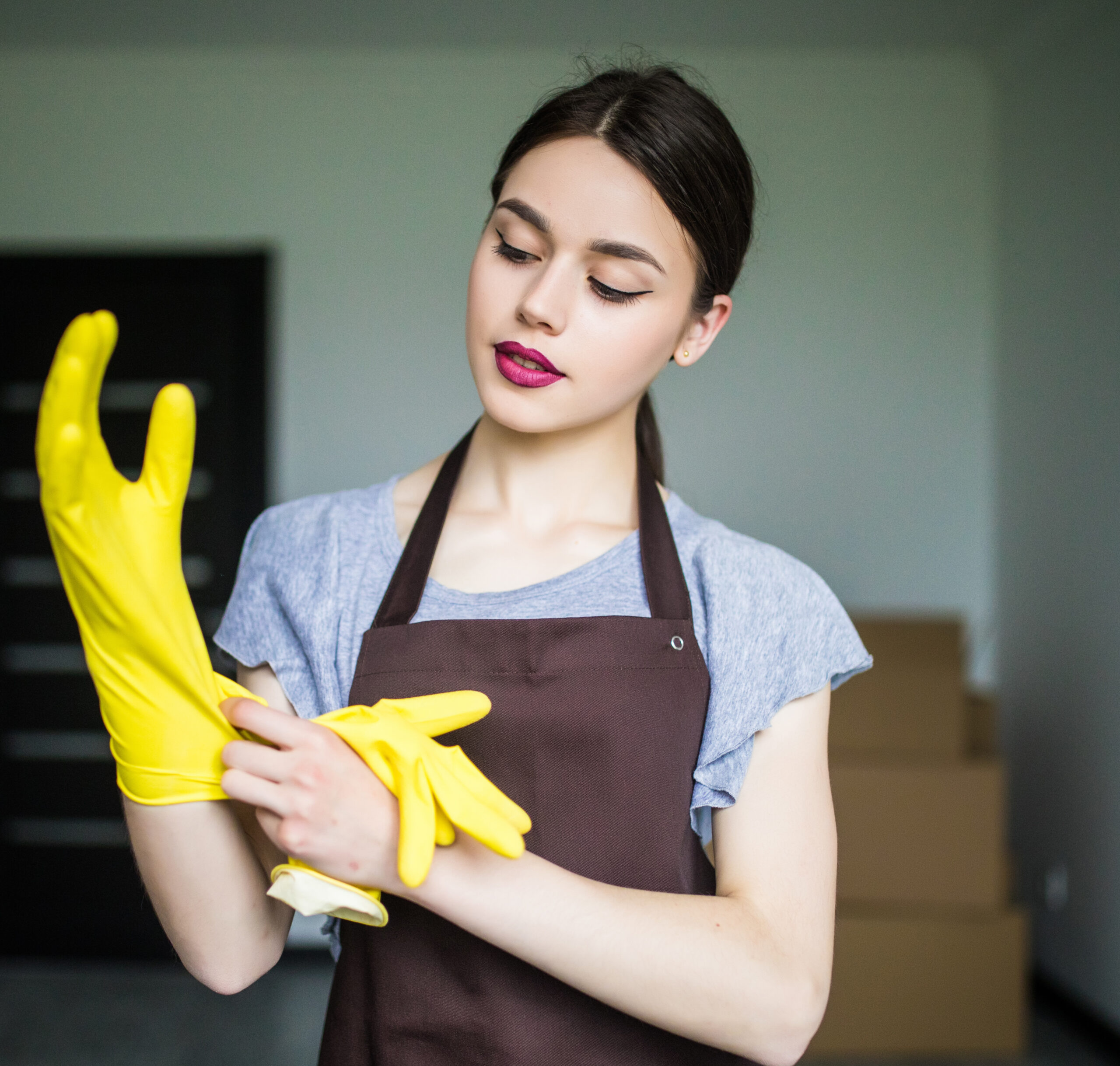 Young cleaning lady putting on rubber gloves, getting ready for spring cleaning
